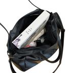 Intérieur doublé du sac noir, un livre et une trousse glissés dans le compartiment principal