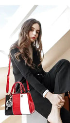 Jeune femme assise en tenue noire, le sac à main rouge, noir et blanc posé au sol contre sa jambe