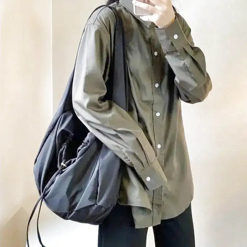 Nylon noir froissé et volume souple, sac porté à l'épaule par-dessus une chemise vert olive