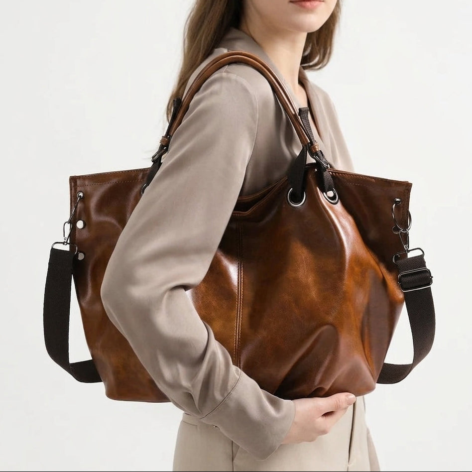 Porté à l'épaule sur un haut beige, le cabas marron s'ouvre en corolle sur son cuir végan huilé