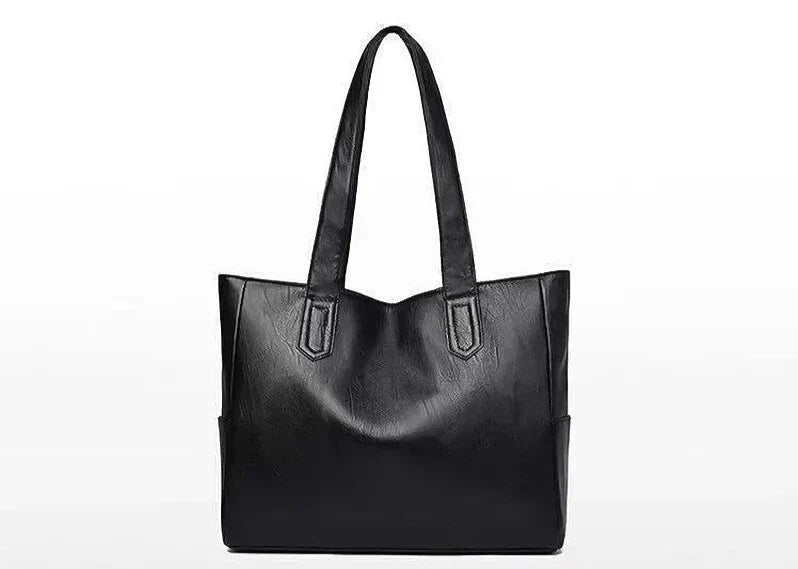 Cuir végan noir lisse, cabas de face, ouverture large sans rabat et flancs légèrement soufflés