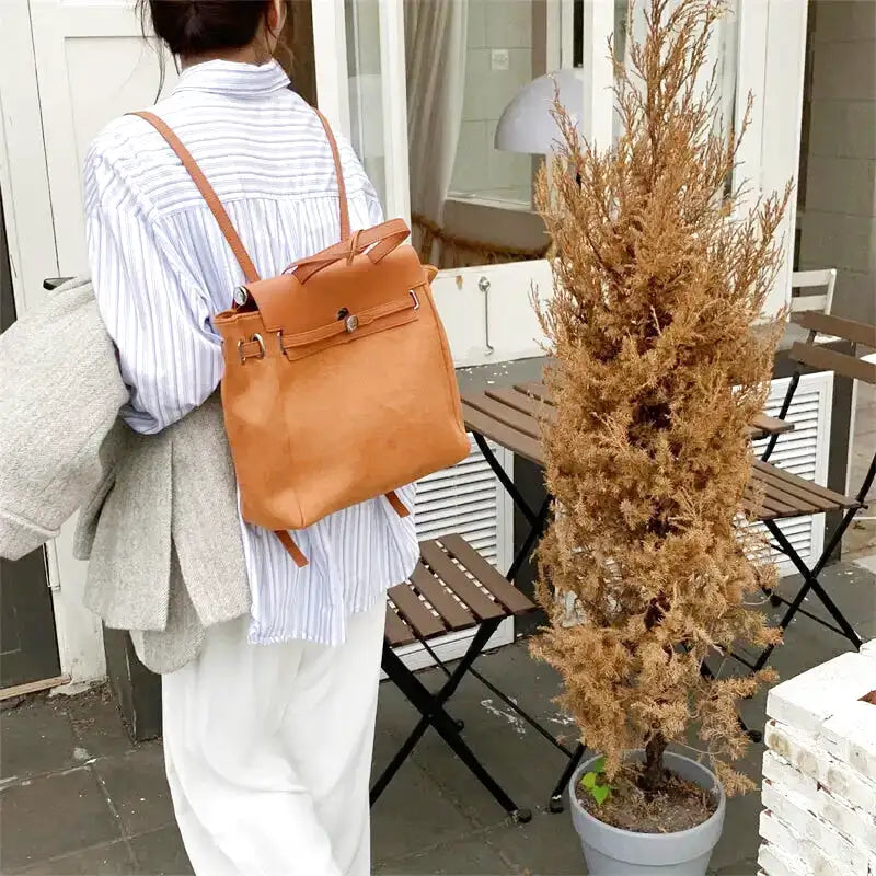 Modèle de dos portant le sac camel haut sur les épaules, bretelles souples et rabat sanglé
