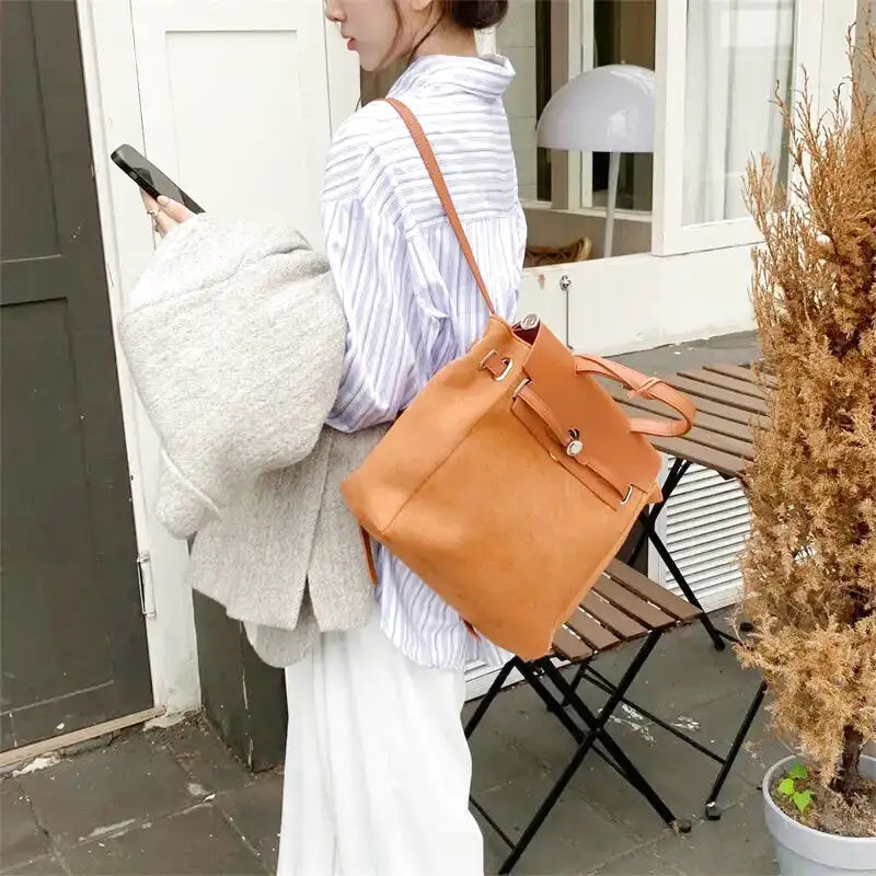 Porté en sac à dos camel sur une chemise rayée bleu et blanc, silhouette de profil en terrasse