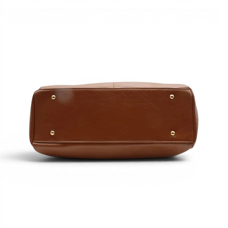 Fond plat du sac camel, protégé par quatre pieds métalliques dorés, cuir végan lisse