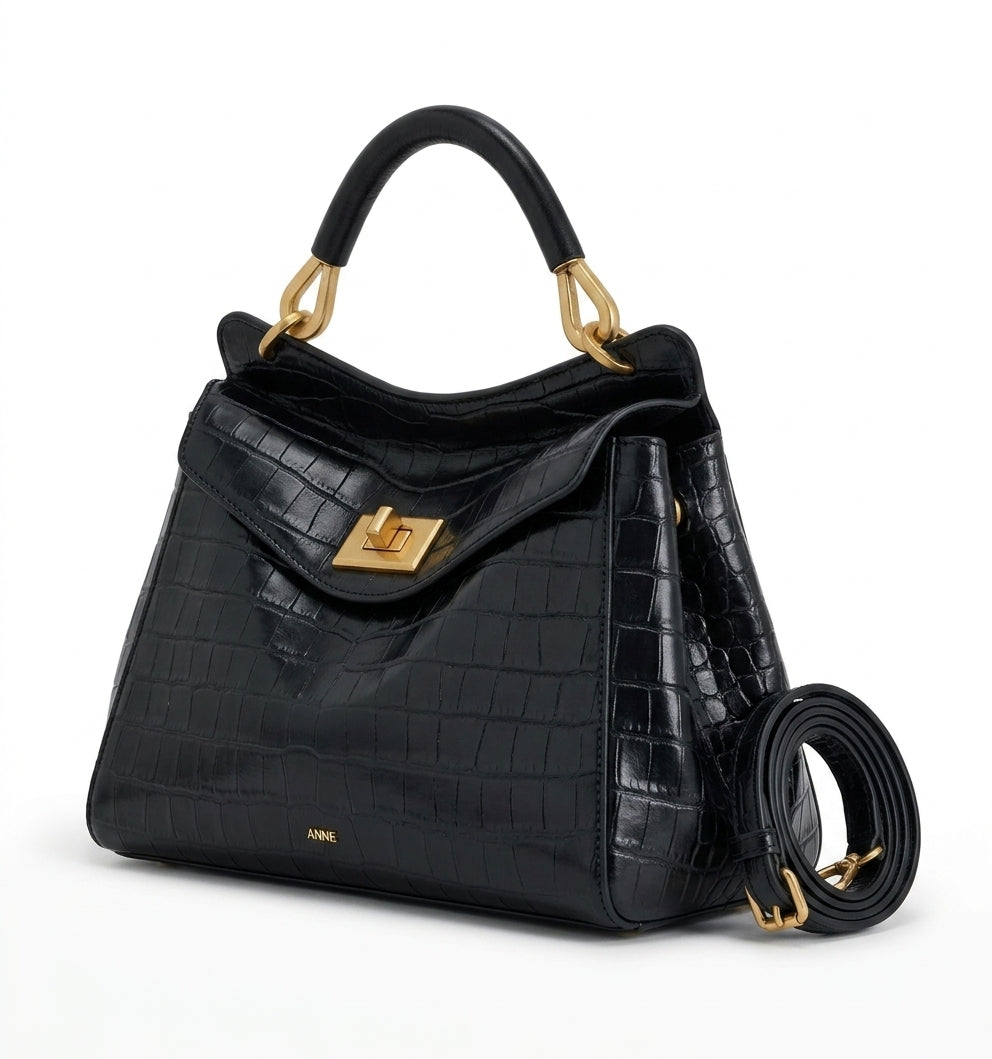 Cuir végan façon croco noir, sac vu de trois quarts, anse arrondie et lanière enroulée à l'arrière