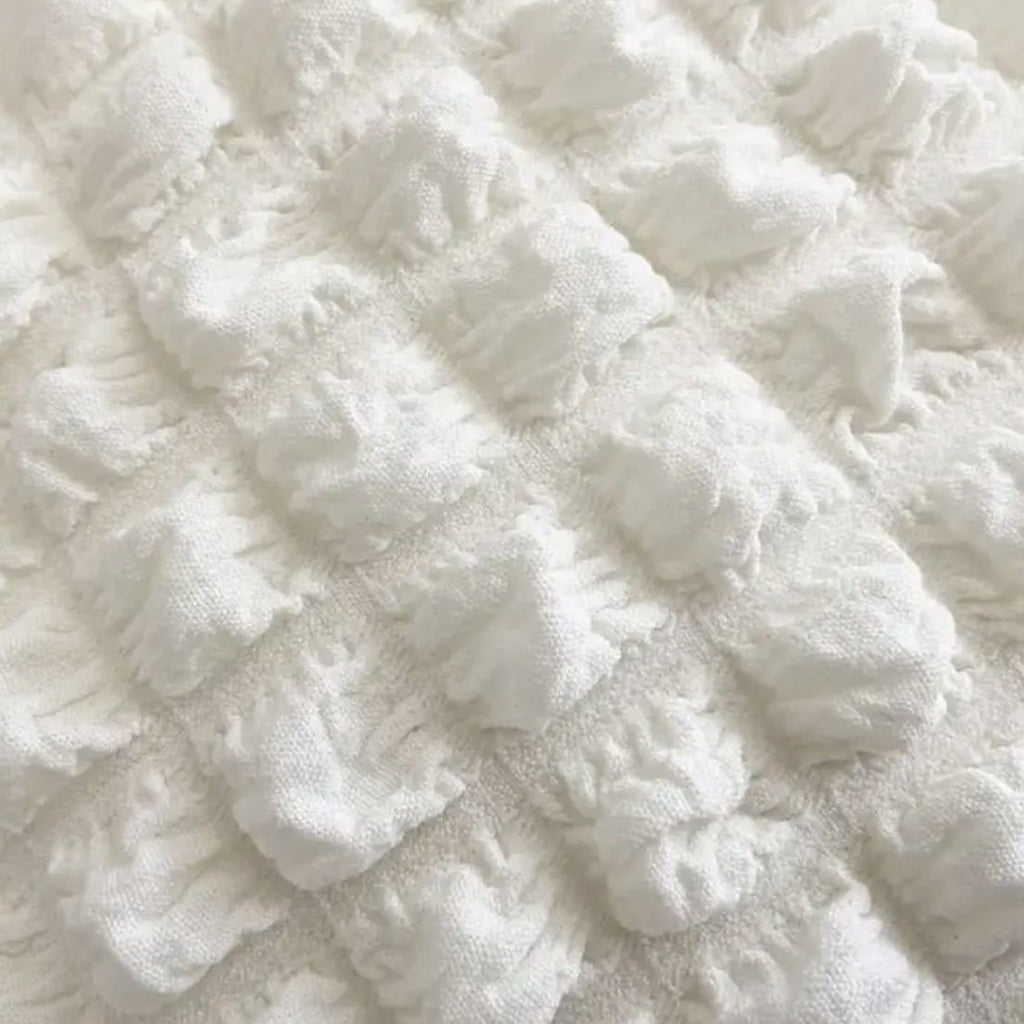 Gros plan sur le tissu gaufré à bulles écru, relief matelassé et grain souple du sac