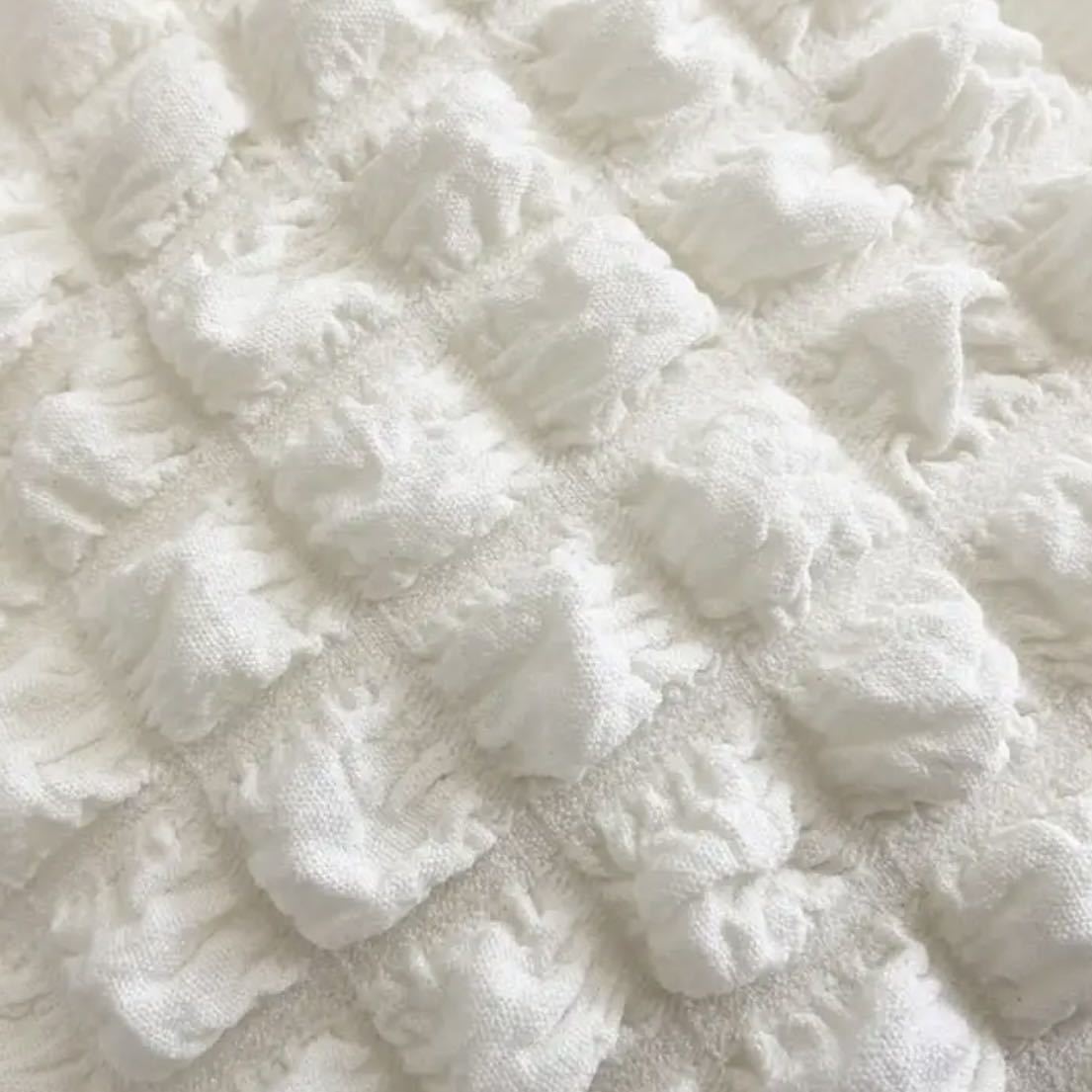 Gros plan sur le tissu gaufré à bulles écru, relief matelassé et grain souple du sac