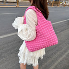 Dans la rue, le grand sac rose vif porté à l'épaule sur une robe blanche à volants