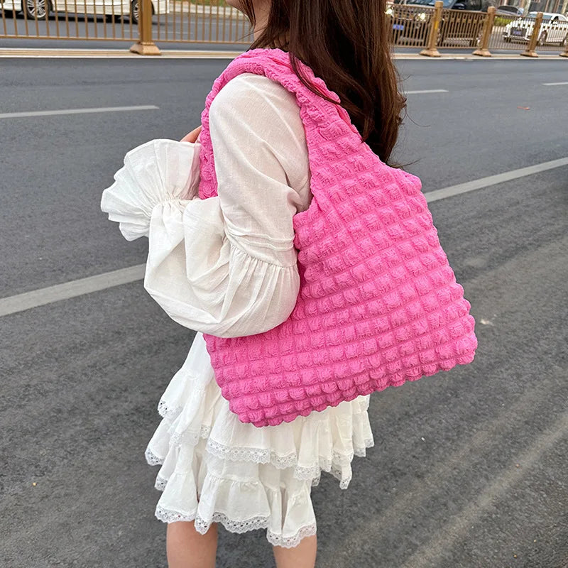 Dans la rue, le grand sac rose vif porté à l'épaule sur une robe blanche à volants