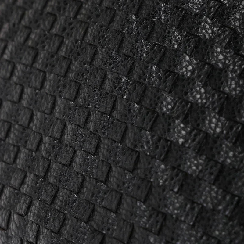 Macro du tressage noir : lanières de cuir végan entrecroisées, grain mat et relief régulier