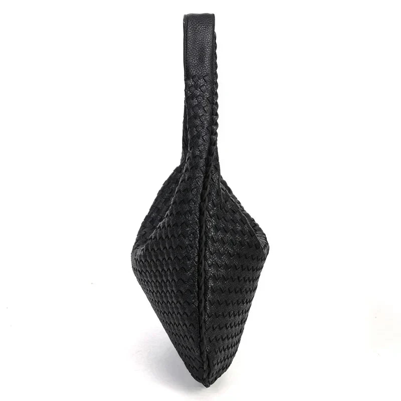 Vu de profil, le sac noir dresse son anse à la verticale et affine sa base en pointe