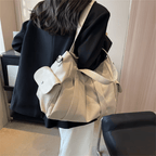 Modèle beige écru porté à l'épaule sur une veste noire, poche latérale à rabat bien visible