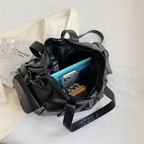 Intérieur du sac noir ouvert sur des cahiers et un classeur bleus, doublure sombre visible