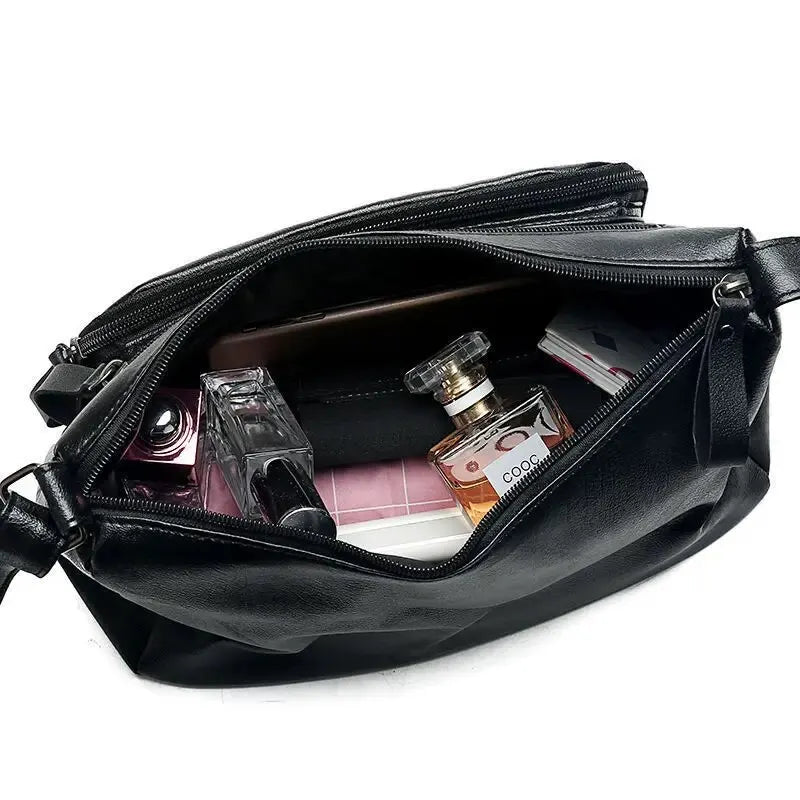 Intérieur ouvert du sac, doubles compartiments zippés garnis d'un flacon de parfum et de maquillage