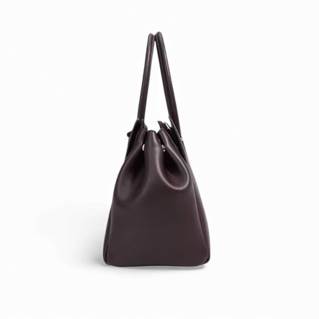 Profil étroit du sac brun aubergine, base rigide et anses rondes rassemblées vers le haut