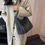 Porté à l'épaule sur un trench beige clair, le hobo gris ardoise et sa large anse d'épaule