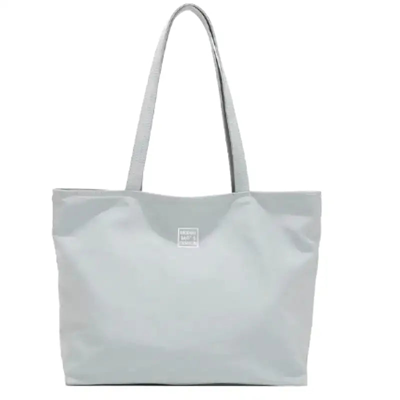 Grand sac fourre-tout gris clair en nylon imperméable, de face, anses fines et flancs plissés