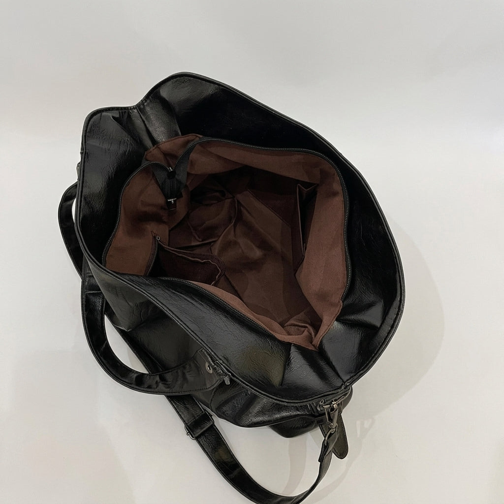 Ouvert sur sa doublure textile brune, le sac noir laisse voir sa poche intérieure zippée et son fond