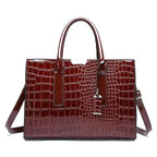 Sac cartable en cuir végan vernis façon croco bordeaux, poignées rigides et bandoulière, vu de face