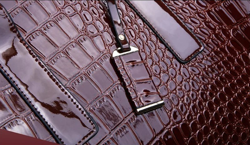 Détail du grain croco vernis et du mousqueton argenté fixé sur la bande verticale du devant