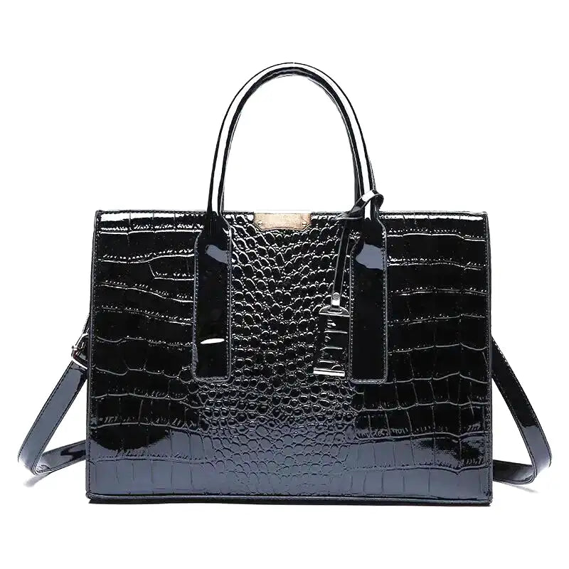 Croco vernis noir sur un sac à main structuré, doubles anses et pendentif métal, présenté de face
