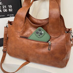 Poche zippée arrière d'un sac marron cognac, smartphone vert engagé dans l'ouverture, tirette visible