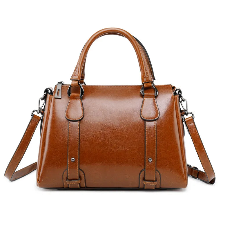 Cognac clair et brillant, le sac est présenté de face avec sa longue bandoulière détachée