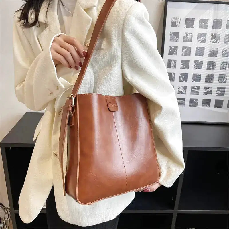 Sac cognac vu de plus près à l'épaule, couture verticale centrale et bordure surpiquée visibles