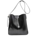Cabas seau noir lustré à fine bandoulière, patte avant et petite pochette zippée sur le côté