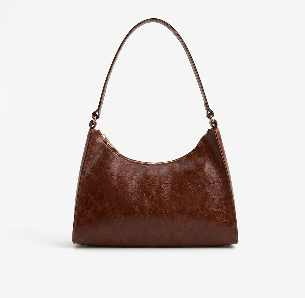 Petit sac marron cognac au grain nuancé, vu de face, anse courte arrondie et base structurée