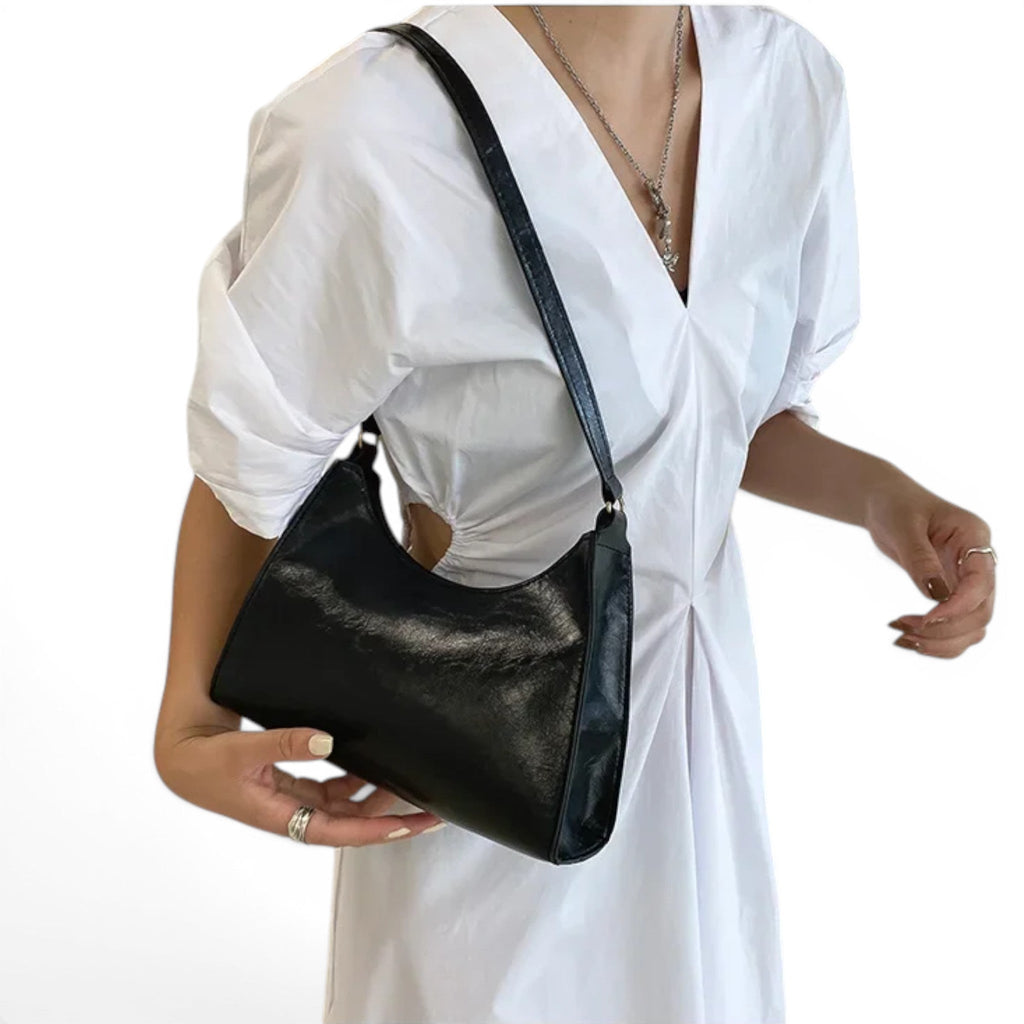 Tenu à la main devant une robe blanche, le hobo noir laisse voir son galbe arrondi et son anse fine