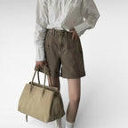 Mannequin en short marron portant le cabas beige taupe à la main, chemise blanche rentrée