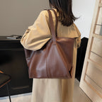Silhouette en trench clair avec le cabas marron à l'épaule, vue de dos dans un intérieur