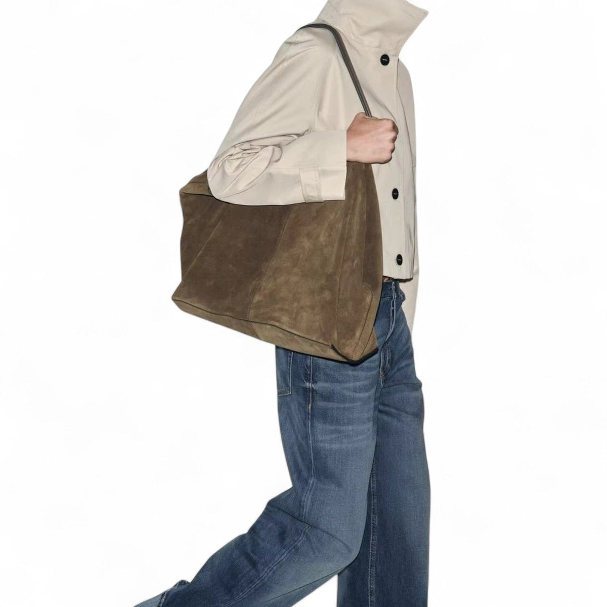Épaule chargée du cabas kaki brun, porté avec un jean et une veste écrue, silhouette en marche