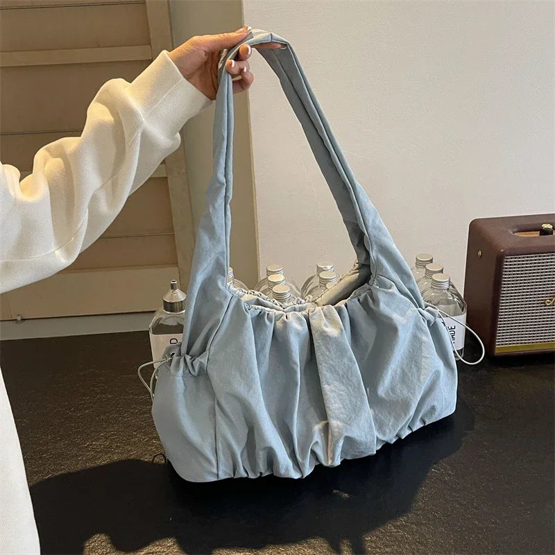 Rempli de bouteilles, le sac bleu gris est soulevé par son anse, fronces du bas bien tendues
