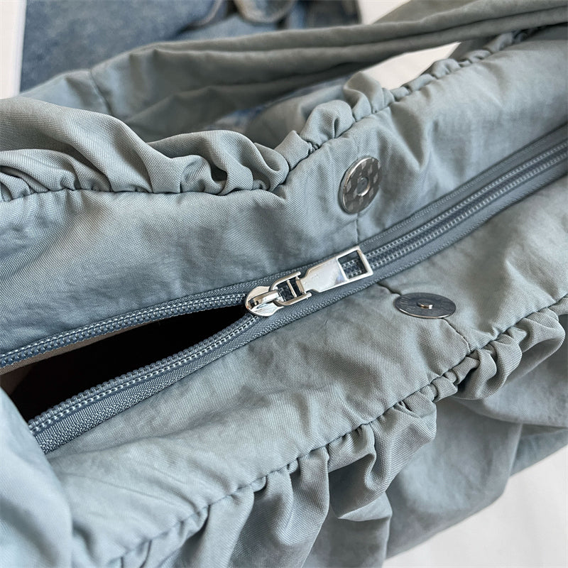 Détail de la fermeture à glissière et des boutons pression métalliques sur le nylon bleu gris