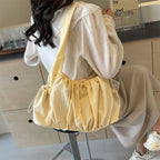 Dans le dos sur une chemise blanche, le sac froncé jaune vanille tombe souplement sous le bras