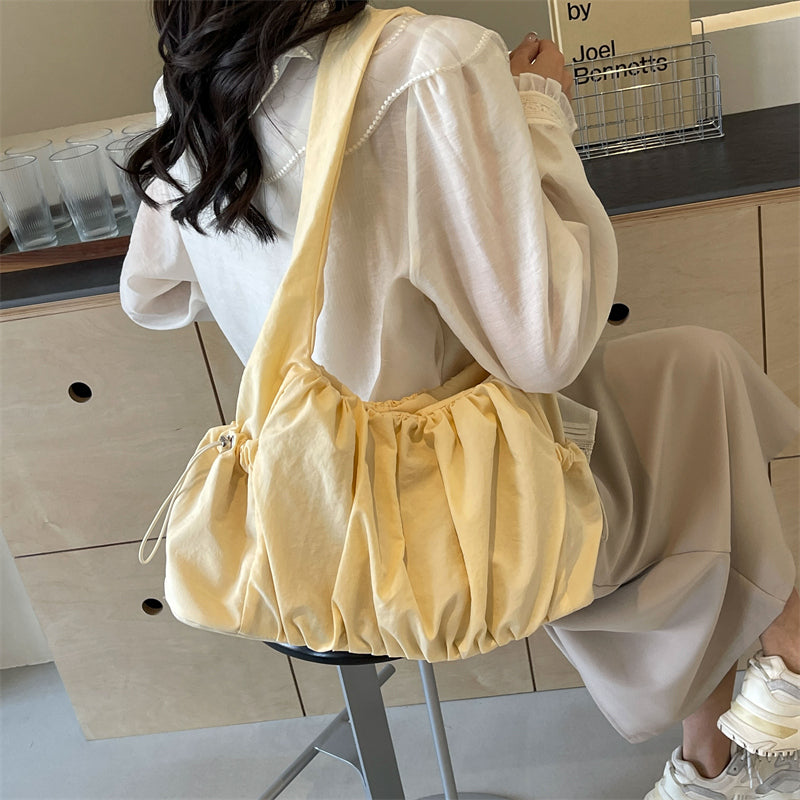 Dans le dos sur une chemise blanche, le sac froncé jaune vanille tombe souplement sous le bras