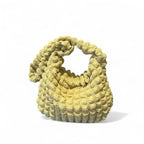 Jaune pâle lumineux, le hobo en tissu gaufré se tient seul sur fond blanc, anse dressée en boucle