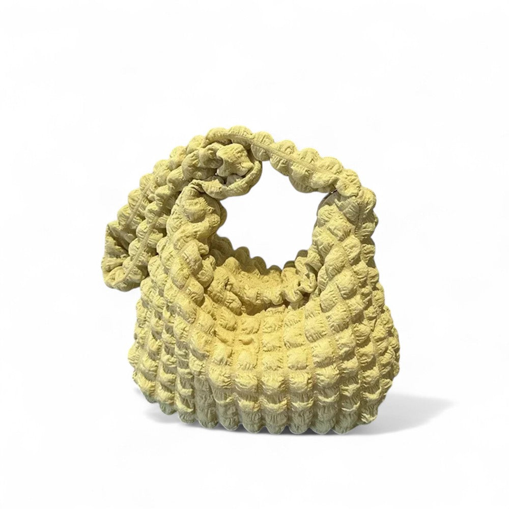 Jaune pâle lumineux, le hobo en tissu gaufré se tient seul sur fond blanc, anse dressée en boucle