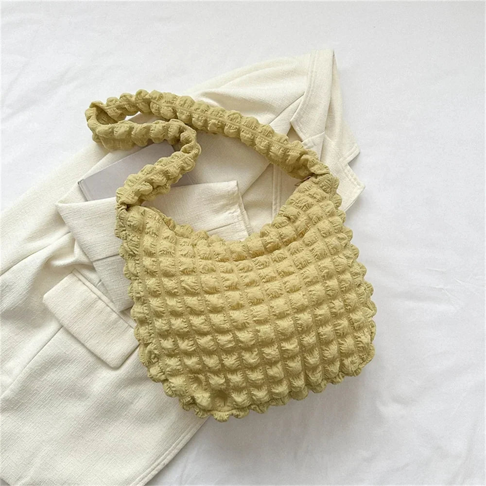 Tissu gaufré jaune pâle, ce hobo posé sur une veste écrue affiche son quadrillage tout en relief