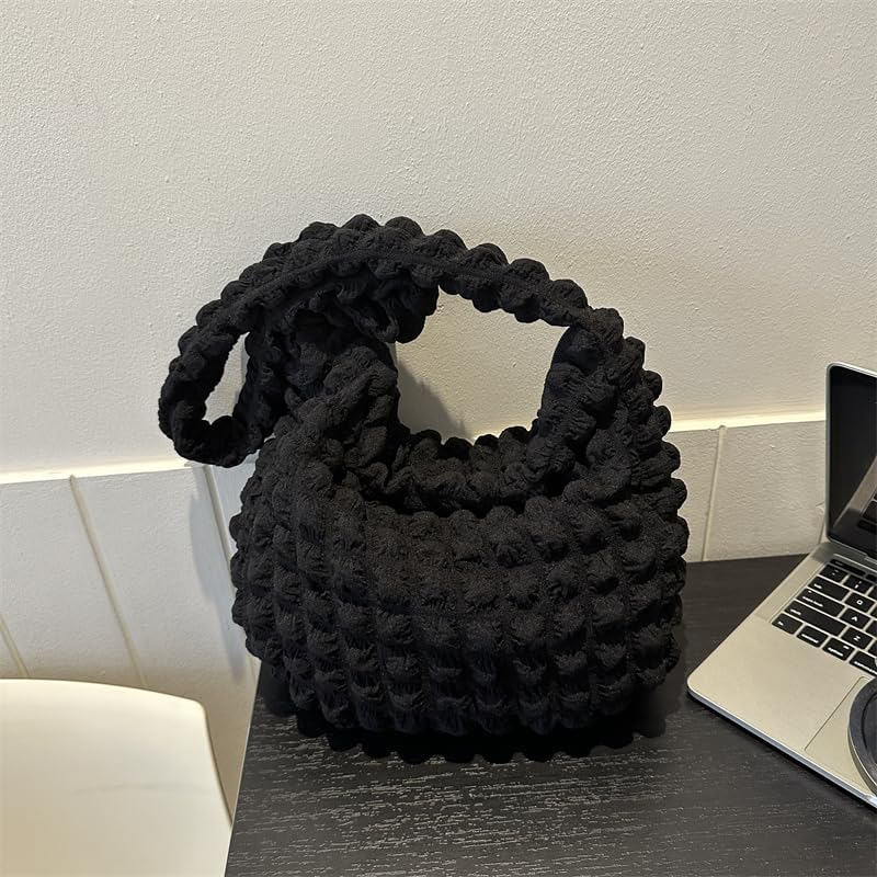 Devant un ordinateur portable, le sac noir texturé attend sur un bureau sombre, anse rabattue
