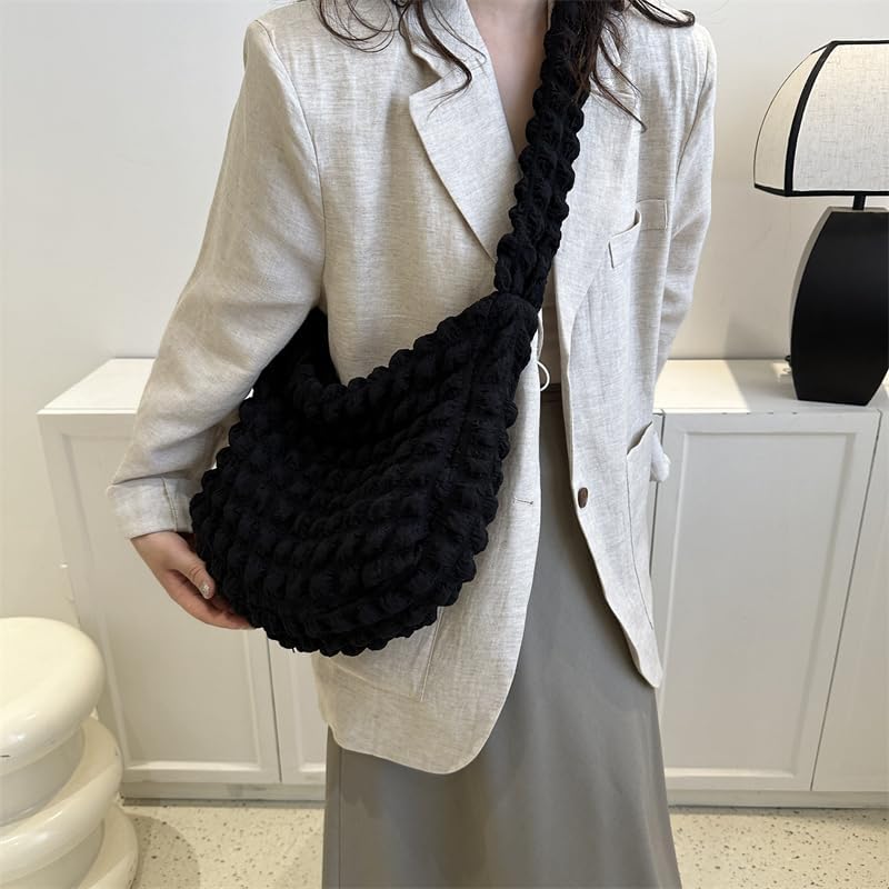 Maintenu contre le buste, le sac noir à texture bulles accompagne une veste écrue et une jupe grise