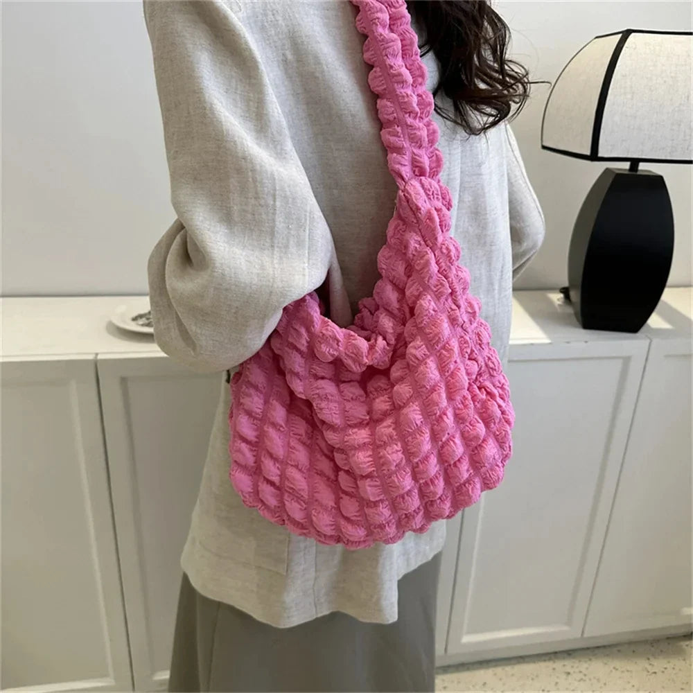 À l'épaule sur une chemise blanche, le hobo rose vif prend un volume arrondi et moelleux