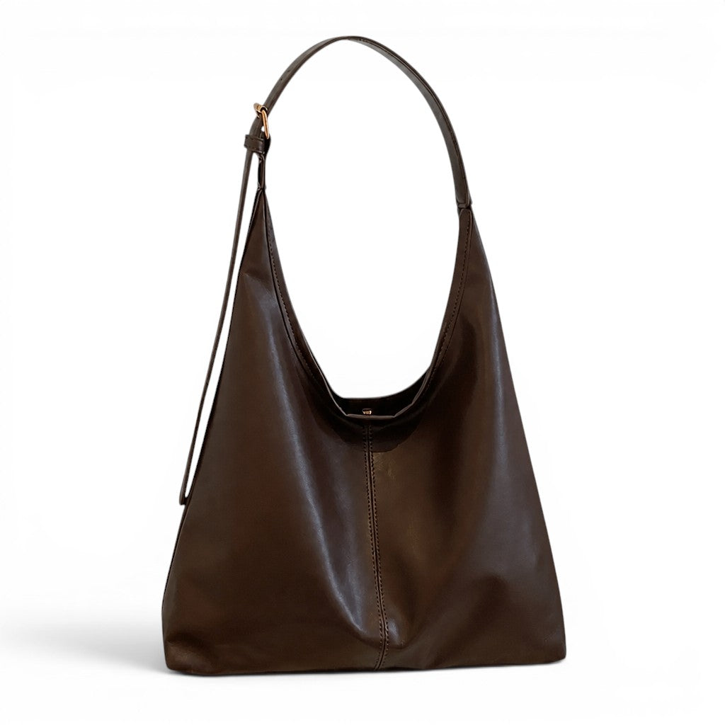 Brun café profond, le sac d'épaule trapèze montre sa couture verticale et sa boucle réglable