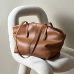 Déposé sur une assise design blanche, le cabas cognac s'affaisse en souplesse, anses tombantes