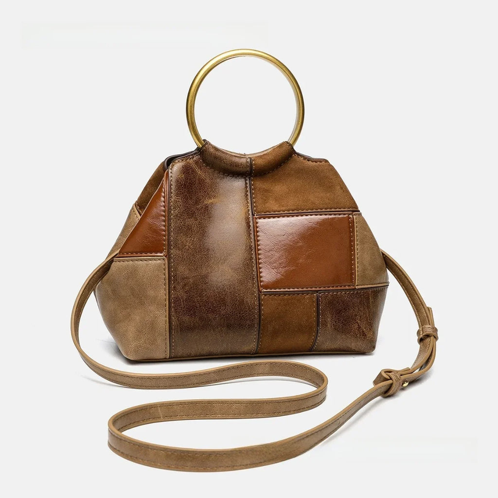 Anse anneau doré et longue bandoulière nouée déployée devant le sac patchwork brun, vu de trois quarts