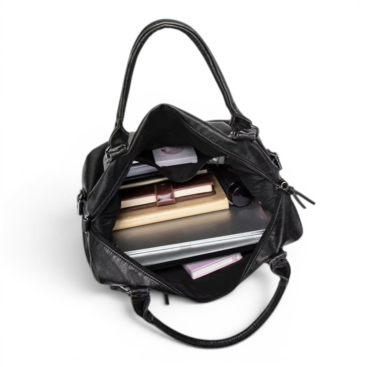 Ouvert par le haut, le sac noir avale un ordinateur portable, des cahiers et une gourde