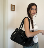 À l'épaule d'une jeune femme en t-shirt blanc, le sac noir tombe le long de la hanche