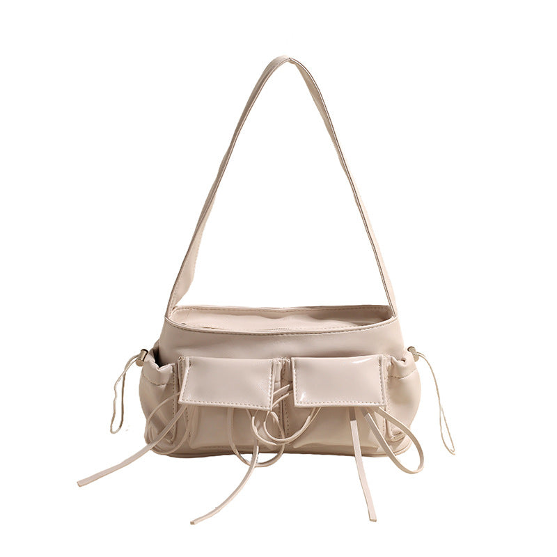 Baguette écru à surpiqûres, poches frontales et cordons noués, présenté de face bandoulière tendue